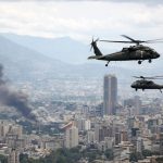U.S. military helicopters fly over Caracas as smoke rises from the city during reported strikes in Venezuela in January 2026.