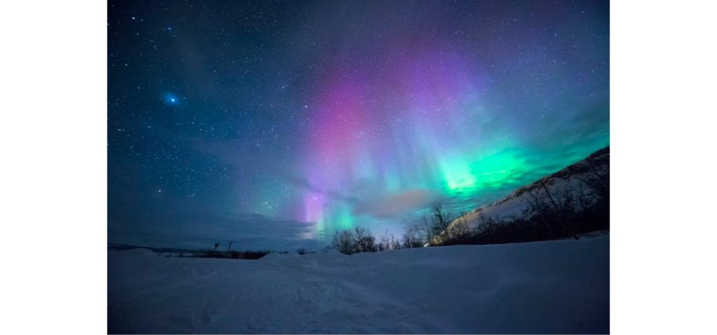 Vivid green and purple aurora borealis over a snow-capped mountain, illustrating tonight's northern lights forecast