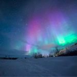 Vivid green and purple aurora borealis over a snow-capped mountain, illustrating tonight's northern lights forecast