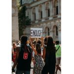 Crowd of young protesters marching with a raised fist and an "Enough" sign during the Cockroach Janta Party protest