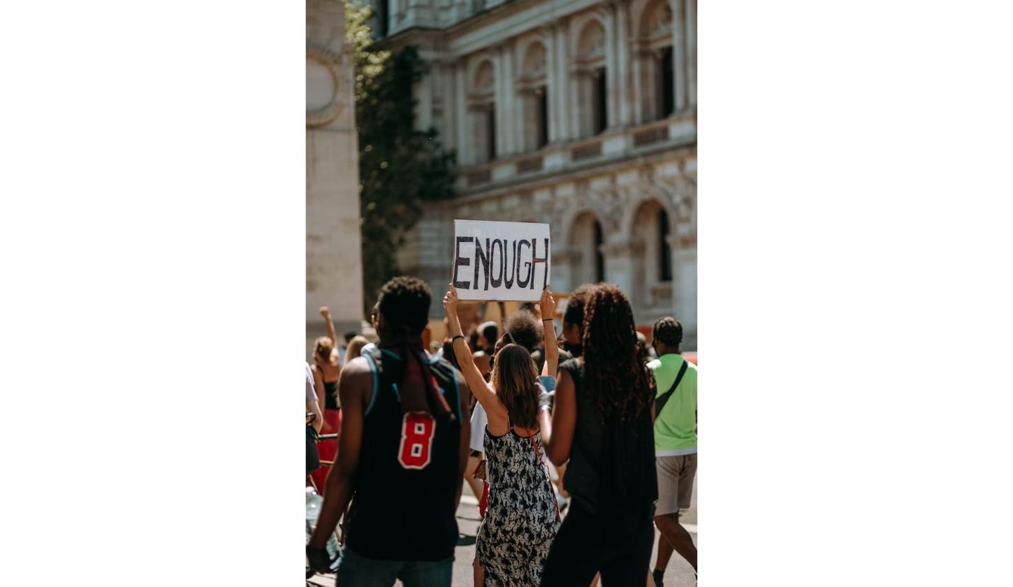 Crowd of young protesters marching with a raised fist and an "Enough" sign during the Cockroach Janta Party protest