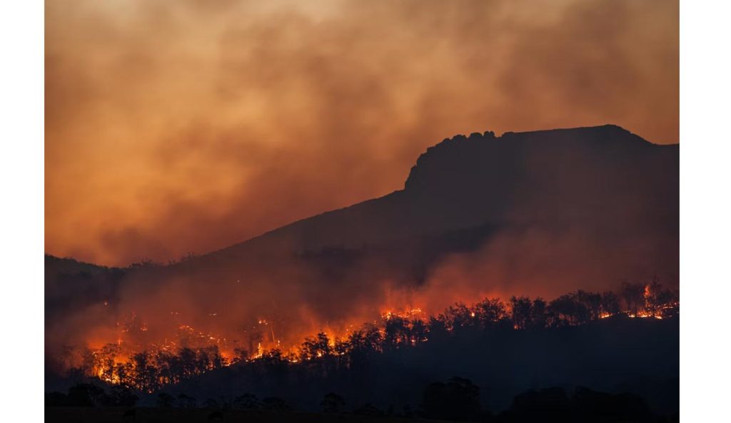 Wildfire burning across a hillside at dusk in southern Europe, with thick smoke rising near Madrid and Bordeaux