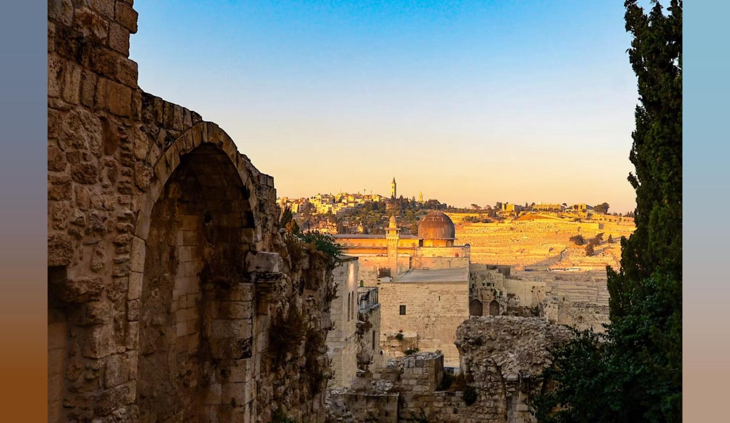 Vivid sunset view of Jerusalem's Old City through an ancient stone arch, evoking the Ark of the Covenant discovery