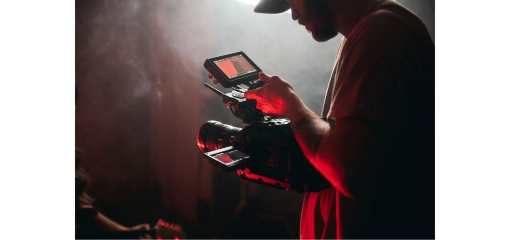 Social media viral trends 2026: filmmaker reviewing red-lit footage on a professional video camera, representing TikTok's Kumar Method