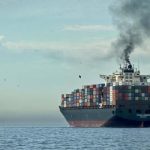 Cargo ship emitting dark smoke at sea, representing the fire aboard LNG tankers after the Damietta port drone attack